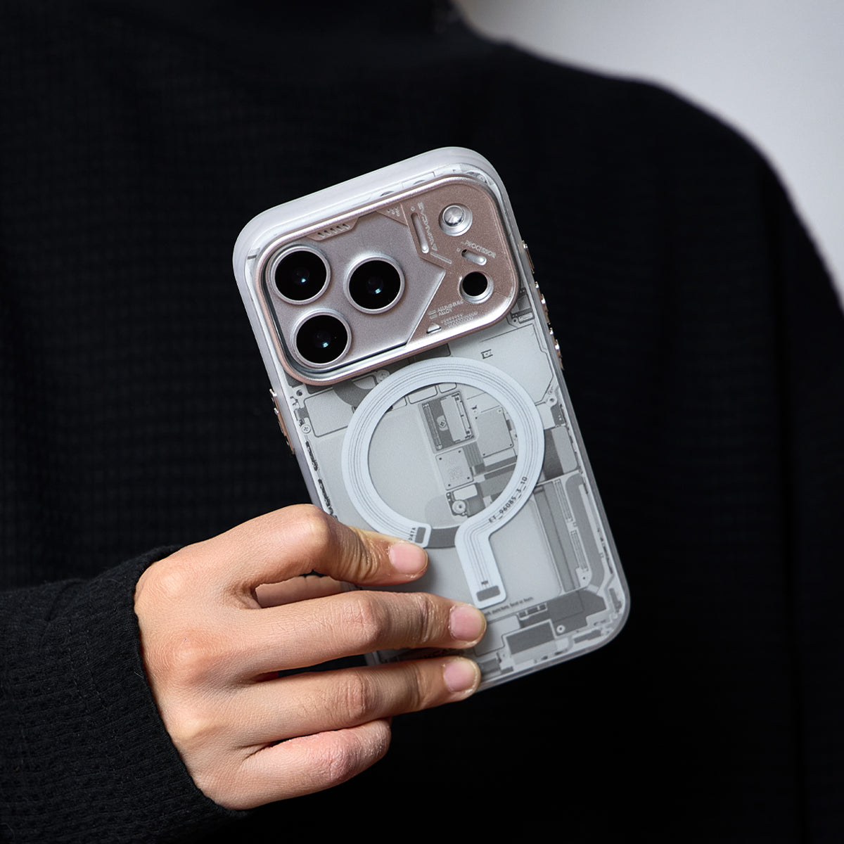 Hand holding the grey circuit board case against a dark sweater