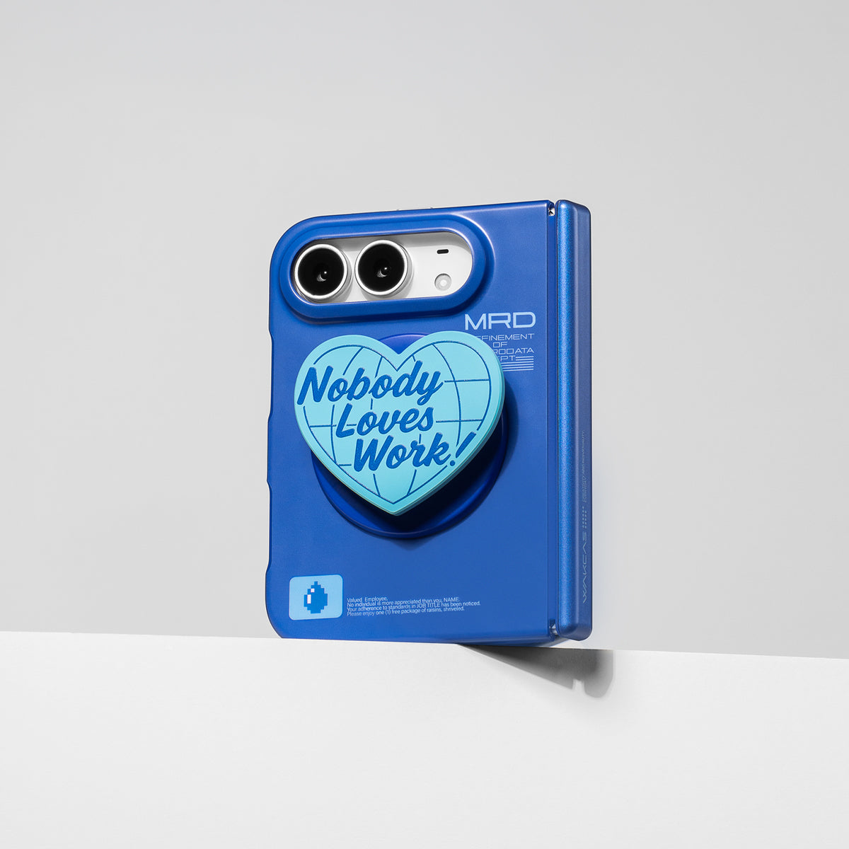 iPhone Duo in the matte blue case with the heart stand attached, standing against a wall