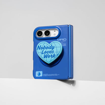 iPhone Duo in the matte blue case with the heart stand attached, standing against a wall