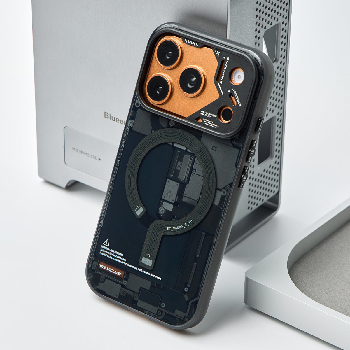 Black circuit board case on an orange iPhone, standing upright