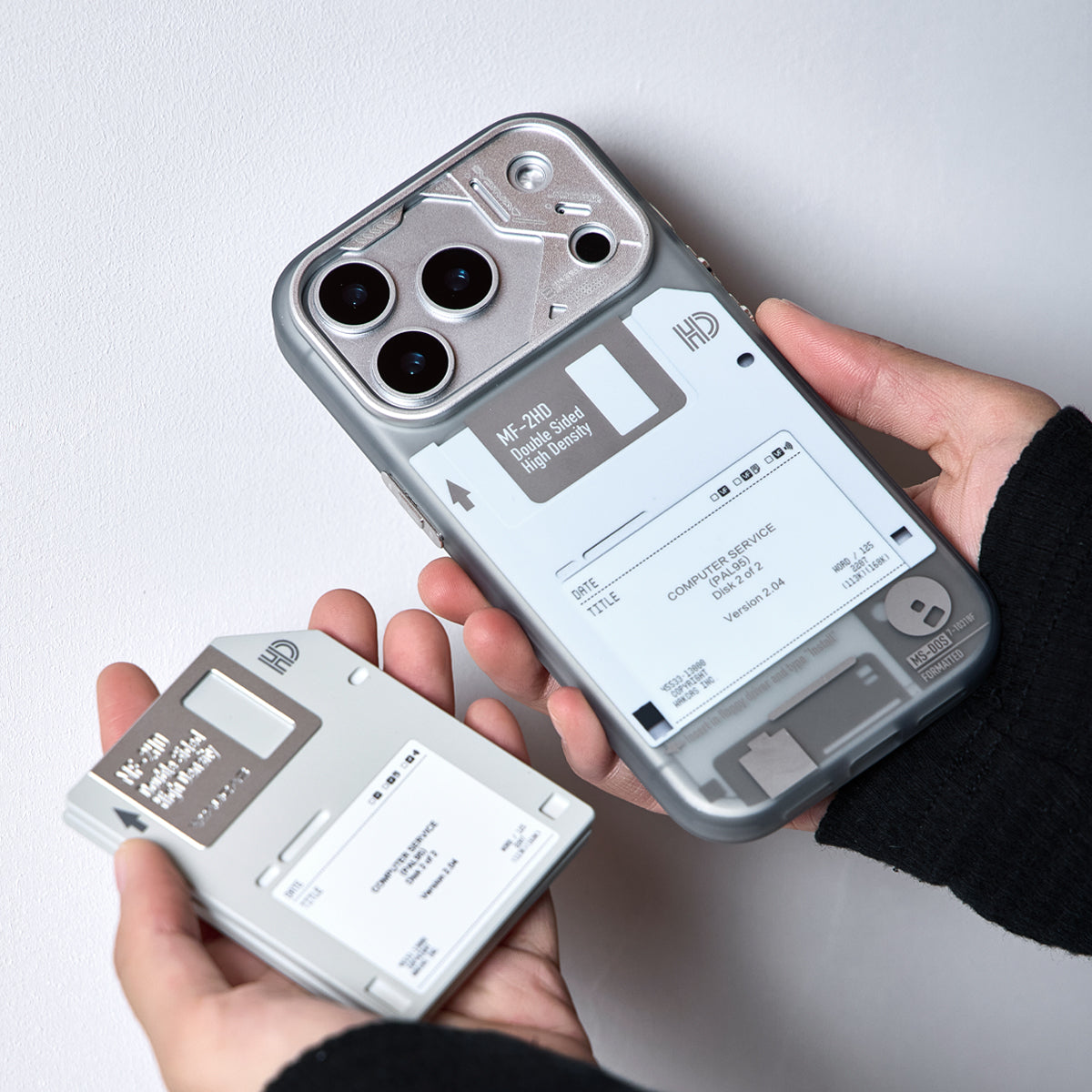 Hands holding an iPhone in a gray case and the floppy disk stand
