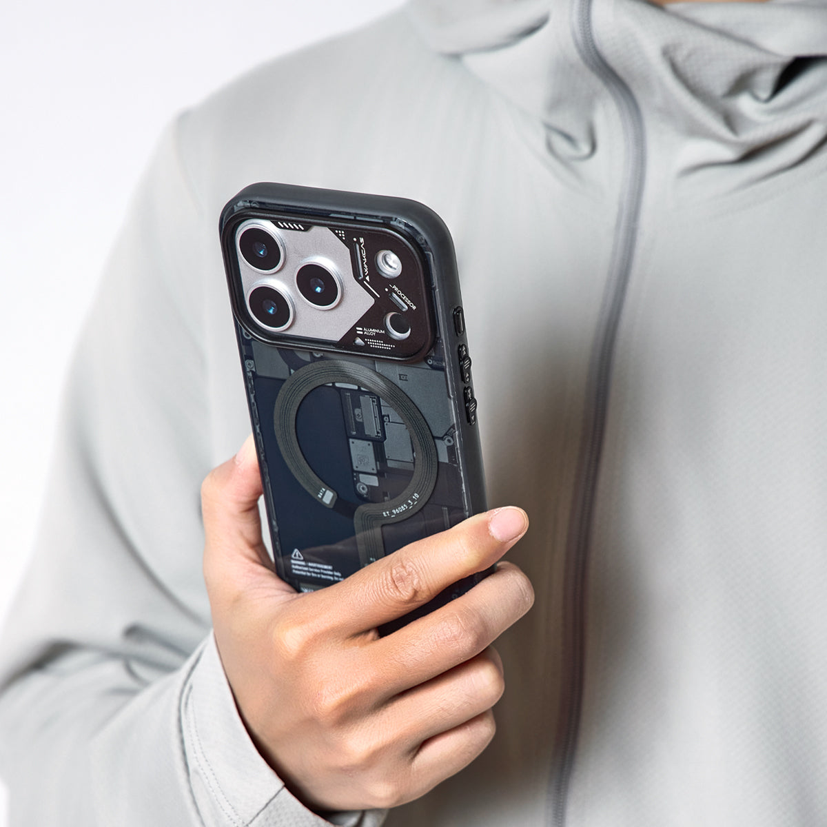 Person holding the black circuit board case in front of a light jacket