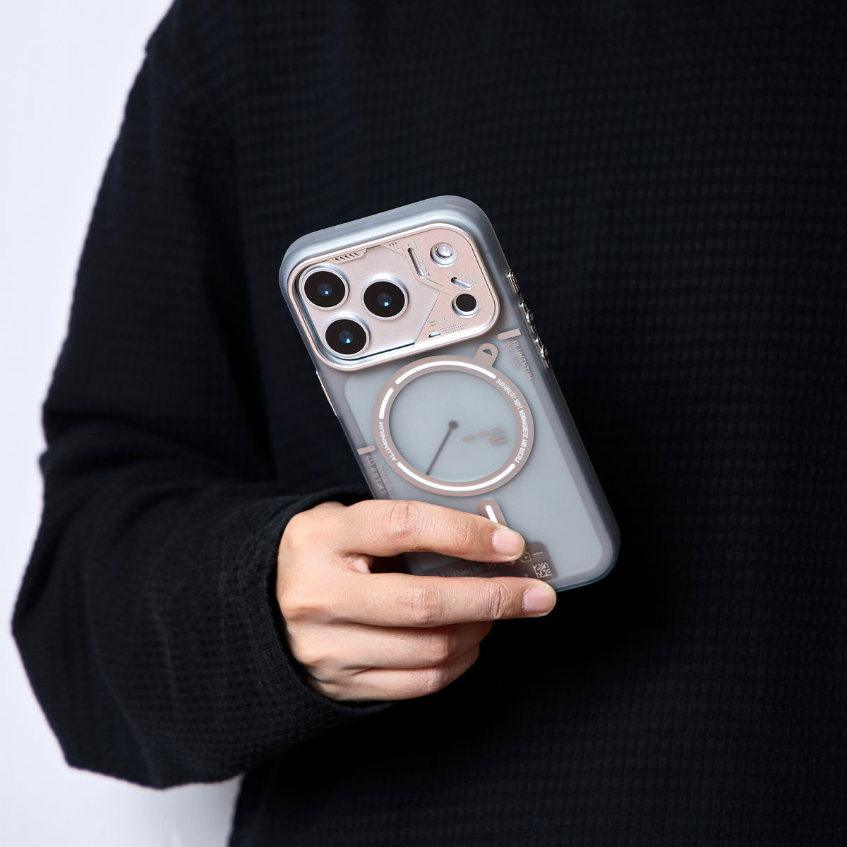 Person holding a frosted translucent case against a dark sweater