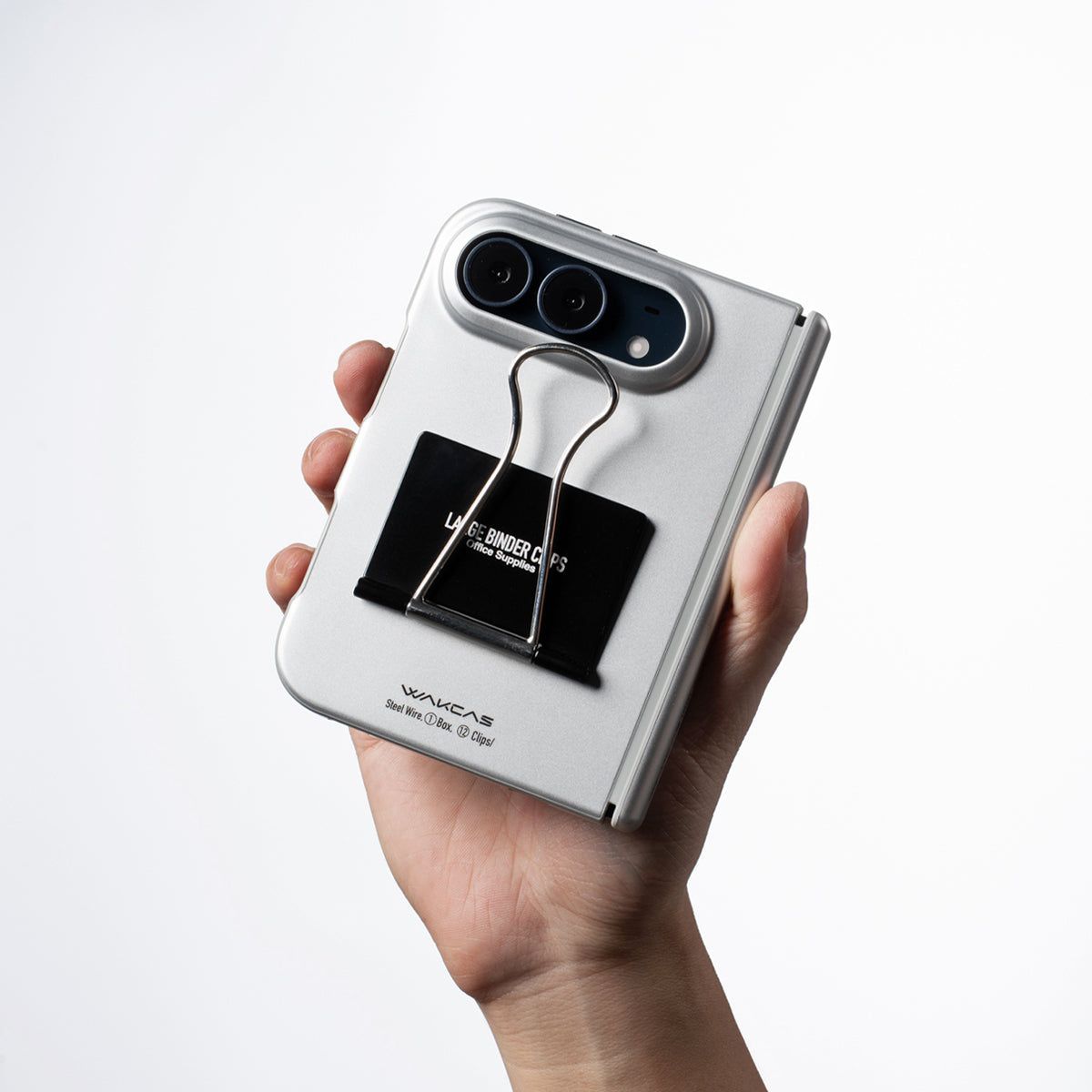 Hand holding an iPhone Duo in the Silver case showing the black label and clip