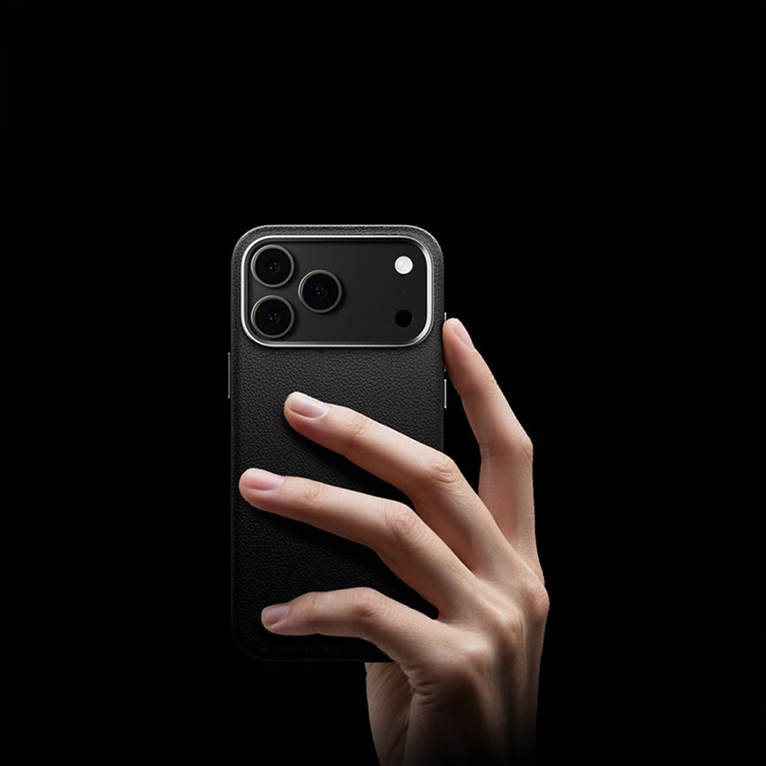 Hand holding an iPhone in a black leather case against a dark background