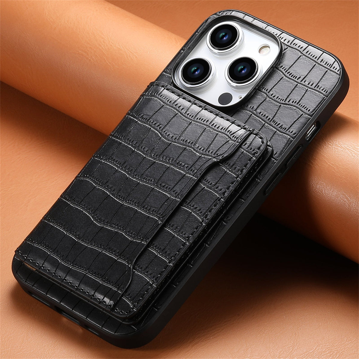 Black crocodile-pattern iPhone case resting on a tan surface, angled view