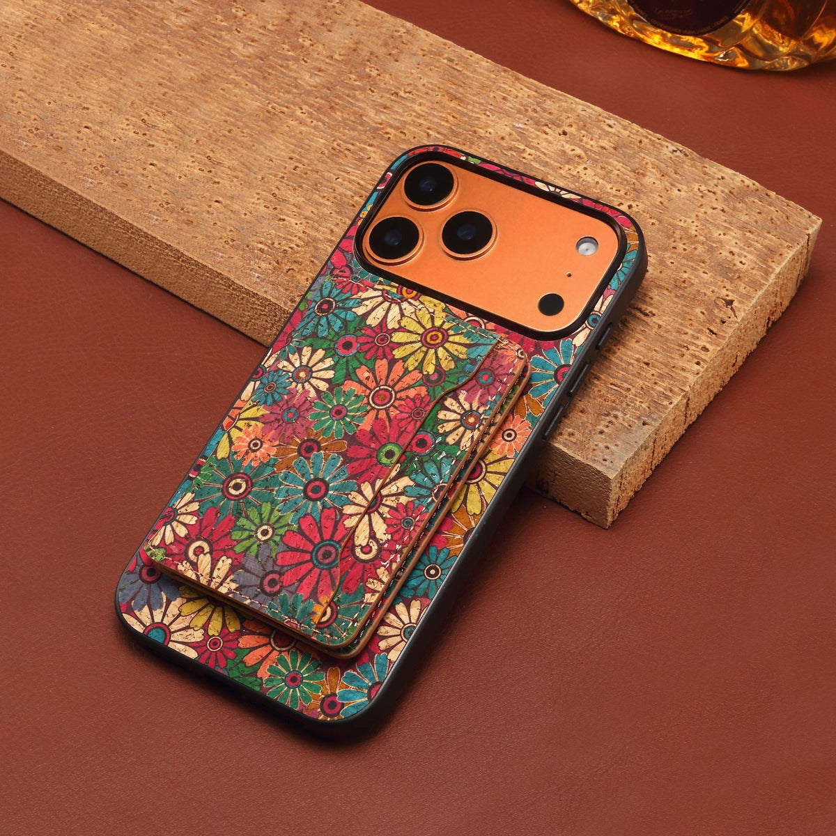 Floral iPhone case with card wallet resting on a wooden block